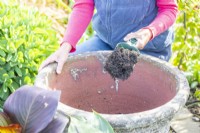 Woman filling large container with compost