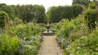 An urn shaped fountain and circular pool in the center of the rose garden surrounded by roses and mixed planting at Newby Hall Gardens.