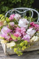 Bouquet of pink and cream - Lathyrus odorata, Dianthus, Lupins, Alchemilla mollis and roses in wooden tray on table