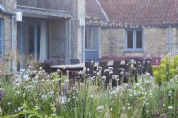 Large outdoor dining space with late May perennial planting. Hailstone Barn Gloucestershire.