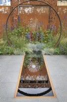 Corten steel moongate and reflections in the pool in the Sunburst garden at RHS Hampton Court Palace Garden Festival 2022