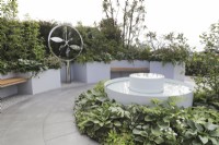 Circular water feature surrounded by green and white planting and circular paving and seating in the CRUK Legacy Garden at Malvern Spring Gardening Festival 2022