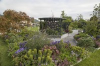 Metal pergola amongst colourful planting in the CRUK Legacy Garden at RHS Malvern Spring Festival 2022