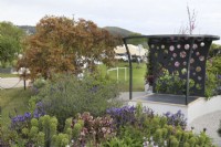Metal pergola amongst colourful planting in the CRUK Legacy Garden at RHS Malvern Spring Festival 2022
