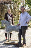 A couple beside a tin horse in their Cornish garden in spring