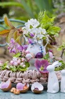 Spring flowers arranged on tiered stand for Easter - cherry blossom twigs, eggs and rabbit ornaments.