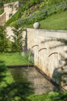 Water spouts from retaining wall into rectangular pond, summer July