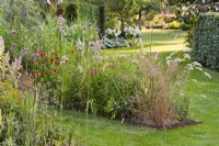 Steel edging flowerbed with grasses and perennials including Deschampsia cespitosa, Melica ciliata, Penstemon and Echinacea.