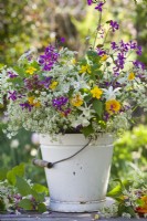 Spring flower bouquet in a bucket containing daffodils  and wild flowers such as dandelion, cow parsley, honesty, buttercup and balm-leaved archangel.