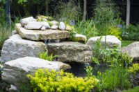 Garden waterfall built with stone boulders. 