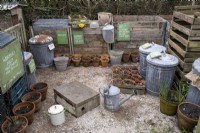 A compost station in a busy garden with various composting bins and a wormery