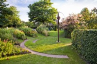 Circular garden with steel edged herbaceous borders, lawn and circular path.