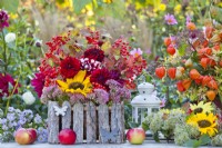 Late summer floral display with sunflowers, dahlias, chinese lantern and guelder rose branches with berries on the table.