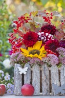 Late summer floral display with sunflowers, dahlias and guelder rose branches with berries on the table.