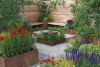 A central water feature is enclosed in Sanguisorba 'Tanna', and surrounded by beds and planters of Helenium 'Moerheim Beauty', Salvia nemorosa 'Caradonna' and ornamental grasses.