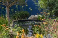 A circular raised pool is enclosed in borders of pines and colourful perennials such as kniphofia, salvias, echinacea, sea holly and coreopsis.
