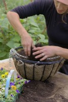 Filling a hanging basket with compost