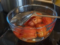 Ripe Roma tomatoes in cold water with skins peeling
