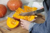 Removing seeds from pumpkin slices with knife, autumn October