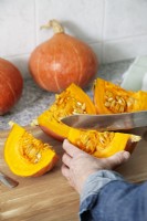 Removing seeds from pumpkin slices with knife, autumn October