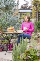 Woman sitting at table in a garden with a cup of tea