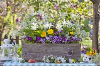 Floral arrangement in wooden box containing daffodils, pansies, dandelion, honesty and cow parsley