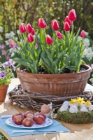 Tulips in terracotta container and Easter eggs on the table.