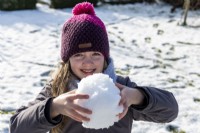 Little girl holding a snowball in her hands