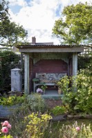 Informal cottage planting around a summerhouse made with recycled materials.