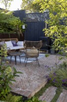 Garden patio in small suburban garden with recycled brick surface and steps