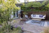 Patio with furniture in suburban garden with garden office in background
