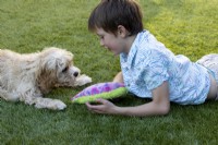 Young boy playing with dog in suburban garden
