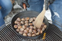 Roasting chestnuts in an iron pan on the barbecue