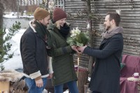 Man presents a woman with Christmas rose wrapped in fir branches