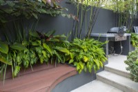 Curved composite timber bench seat in an innercity courtyard garden with steps leading to an upper level.