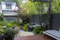 Inner city courtyard garden with a deck, bench seats raised garden beds and barbecue.