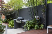 Bespoke bar-be-cue bench next to raised garden beds and artificial timber deck.