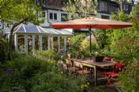 Small town cottage style garden built with wildlife in mind, large orange sunshade provides shade over garden table and chairs