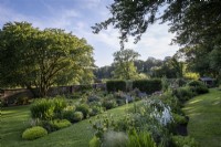 Deep perennial summer borders, with shading trees surrounding.