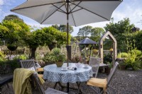 Gravel patio area with outdoor garden table and chairs, parasol and chiminea