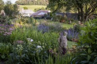 Classical statue of a woman, hidden amongst deep perennial summer borders, in a country garden in Cornwall