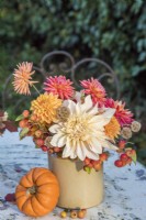 Arrangement of Dahlias and crab apples arranged in pottery vase on metal table