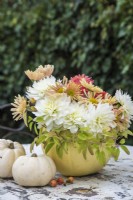 White and peach Dahlias and Chrysanthemums arranged in white pumpkin on white metal table