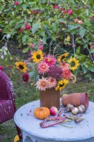 Autumn bouquet of flowers arranged in pottery vase on grey table in orchard - Dahlias, Sunflowers; Sedum and foraged foliage