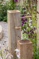 Bird feeder made with posts and wooden spoons, planting of Penstemon and Sanguisorba - The Wooden Spoon Garden - RHS Hampton Court Palace Garden Festival 2022