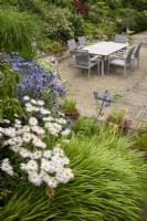 Courtyard garden with dining area surrounded by plants in the garden at Cow Close Cottage, North Yorkshire in July