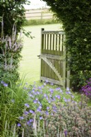 Gate from the ornamental garden into adjoining field, with Geranium Rozanne and Hylotelephium 'Red Cauli' in the foreground at Cow Close Cottage, North Yorkshire in July