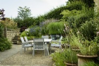 Courtyard garden with dining area surrounded by pots and raised beds at Cow Close Cottage, North Yorkshire in July