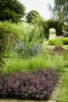 Border planted with Hylotelephium telephium (Atropurpureum Group) 'Karfunkelstein', grasses, eryngiums and Knautia macedonica at Cow Close Cottage, North Yorkshire in July