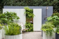 Corrugated steel containers with Carex 'Ice Dancer' and pond plants, green living wall and outdoor shower - The Hot Tin Roof Garden, RHS Chelsea Flower Show 2021